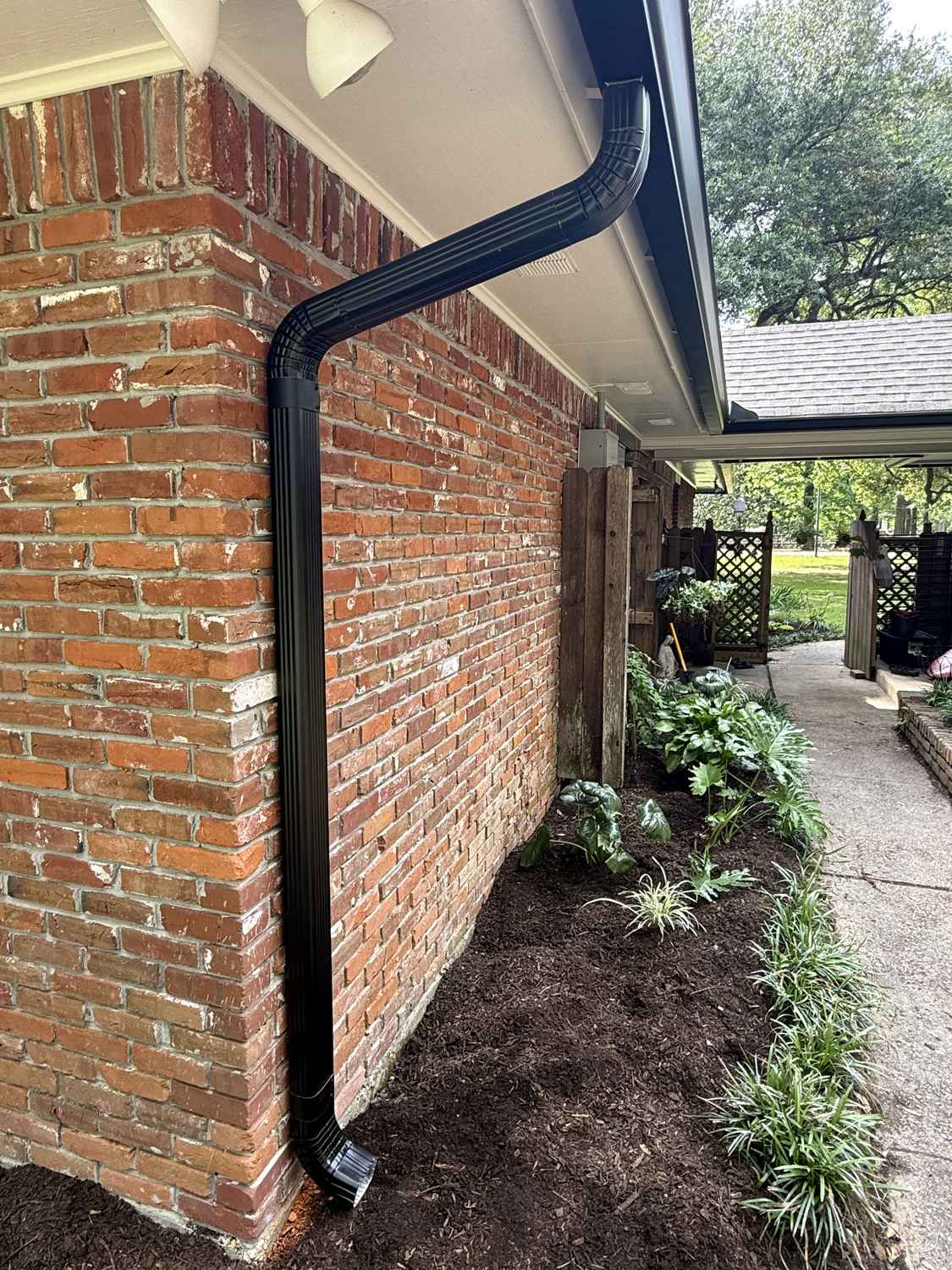 Black seamless gutter and downspout installation on a brick home in Louisiana