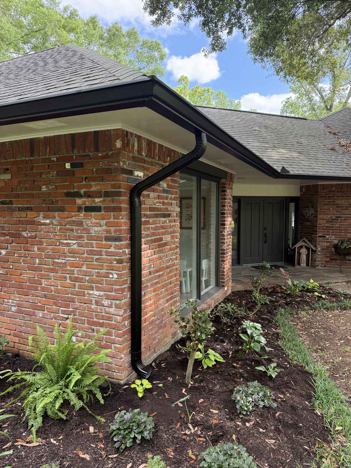 New black seamless gutters and downspout on a brick home in Ascension Parish