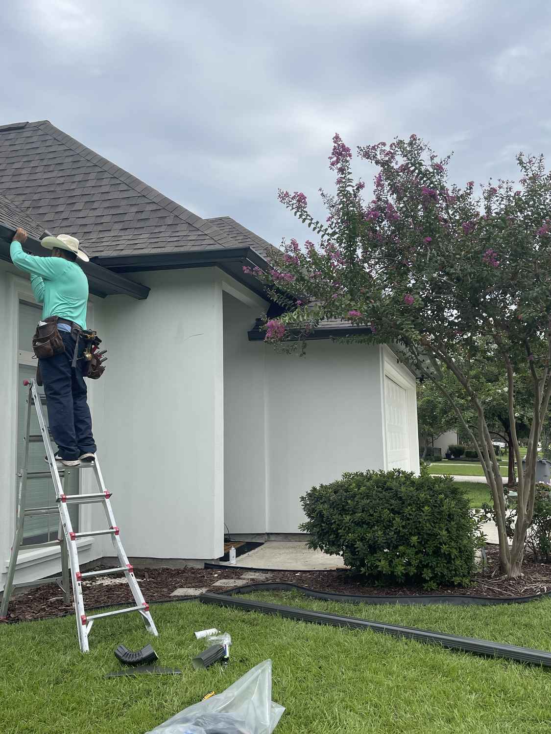 Exterior Pros technician cleaning gutters from a ladder at a Louisiana home