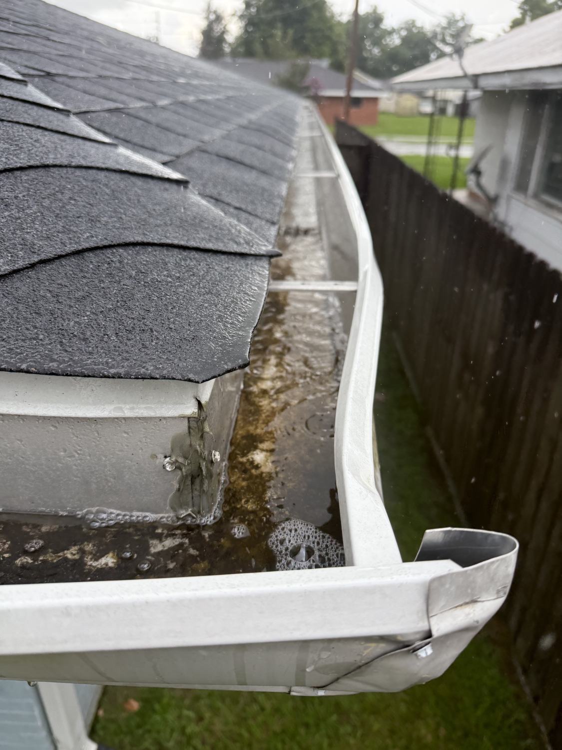 Gutter holding standing water above a downspout on a Louisiana home