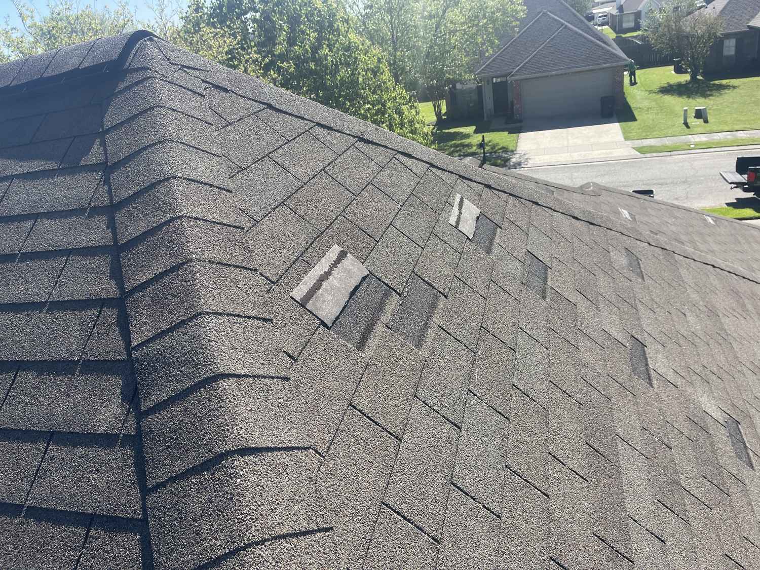 Storm-damaged shingles with missing and lifted tabs on a Louisiana roof